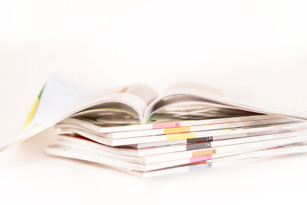 Stack of printed catalogues with one open on top, showing perfect-bound spines