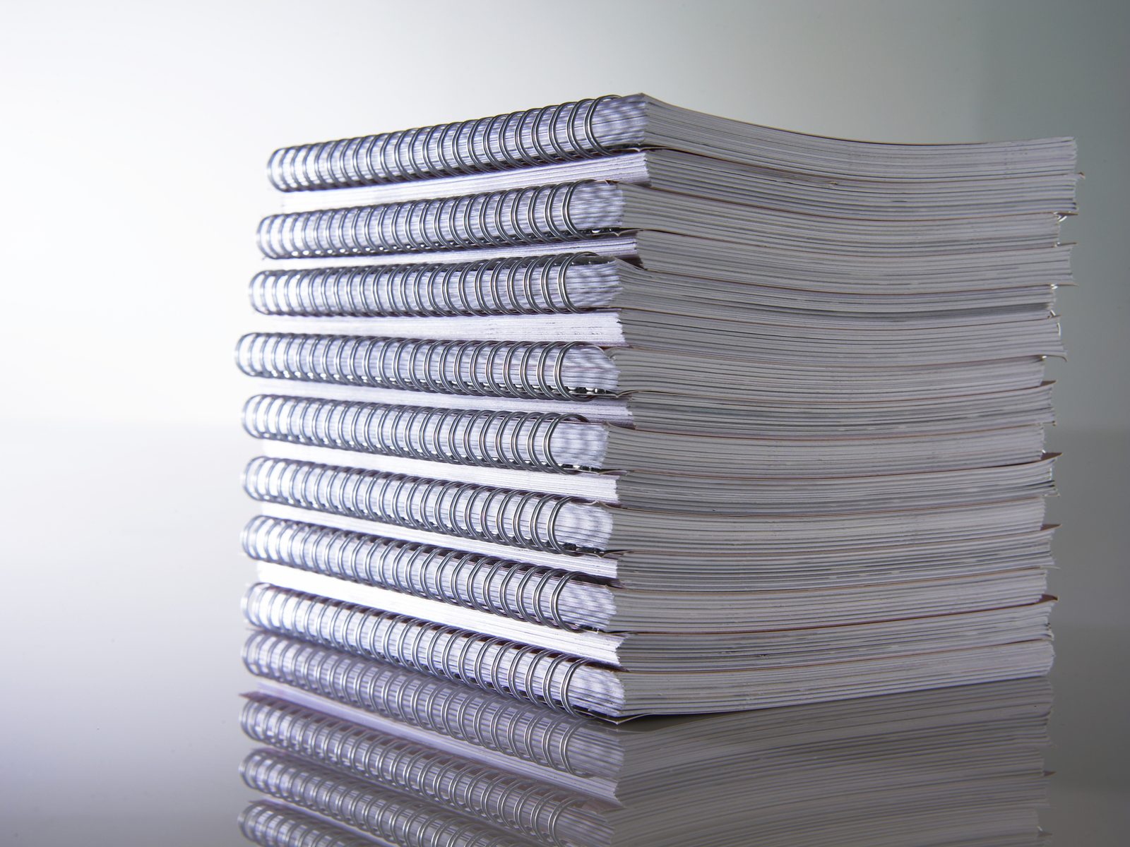 Stack of wire bound booklets with a metal spiral along the edge